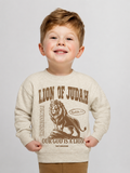 Toddler boy smiling, wearing a heather grey fleece crewneck with a brown graphic reading "Lion of Judah," an illustration of a crowned lion with "Revelation 5:5" in a small banner beside it, and "Our God is a Lion" beneath.