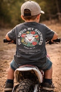 Toddler boy on a dirt bike wearing kids Psalm 23 tee with "The Lord Is My Shepherd" lamb graphic